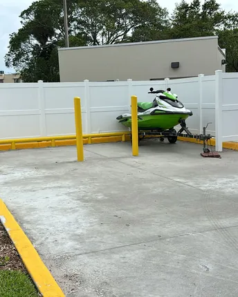 A finished asphalt parking area with fresh curbing and protective bollards on a completed project.