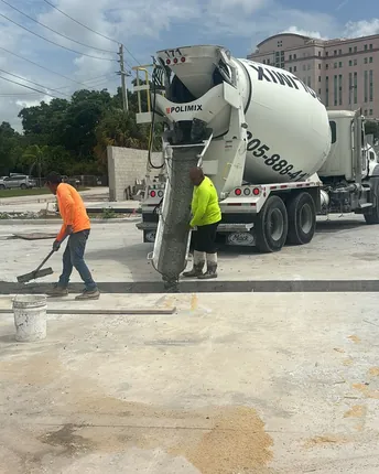 A concrete mixer truck delivering a slab pour while the crew screeds the fresh concrete.